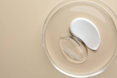 Petri kabında bej arka planda farklı kozmetik ürünleri, üst görünüm. Metin için boşluk