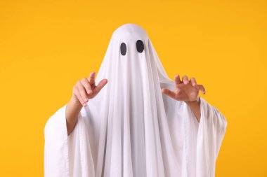 Ürkütücü hayalet. Turuncu arka planda beyaz çarşaflı bir adam.