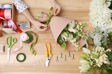 Çiçek buketi yapan bir çiçekçi, ahşap masa, üst manzara