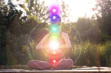 Lotus 'ta meditasyon yapan kadın doğada poz veriyor. Yedi çakra parlıyor