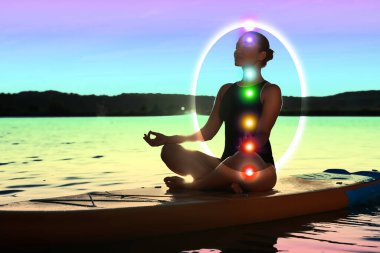Lotus 'ta meditasyon yapan kadın SUP tahtasında poz veriyor. Aura onun etrafında kabarcık olarak görülüyor. Yedi çakra parlıyor