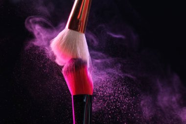 Renkli göz gölgeli makyaj fırçaları siyah arka planda neon ışıkları, yakın plan