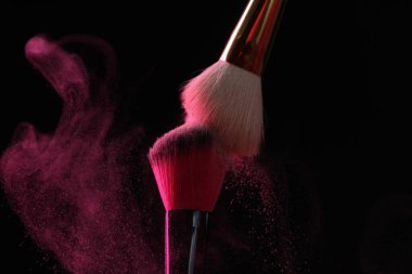 Siyah arka planda pembe göz farlı makyaj fırçaları, yakın plan