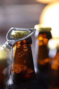 Bulanık gri arka planda bira şişesi açılıyor. Yakın plan.