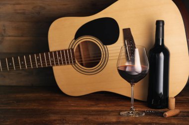 Akustik gitar, şişe ve bir bardak kırmızı şarap.