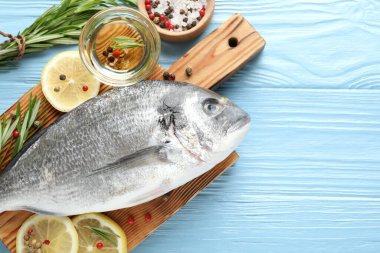 Mavi ahşap masa üzerinde baharatlı taze çiğ dourade balığı, düz ve metin için alan. Deniz ürünleri lezzetleri.