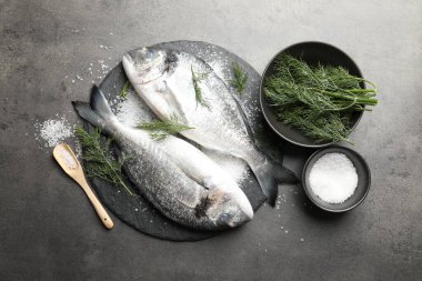 Organik deniz ürünleri. Taze çiğ dorado balığı, gri masada tuz ve dereotu.