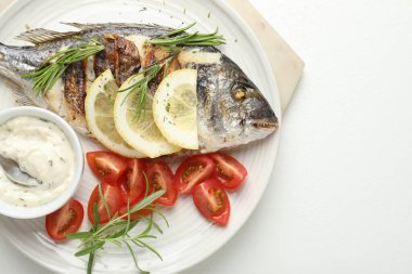 Sos, domates ve limonlu fırında Dorado balığı, beyaz masa, üst manzara ve yazı için yer. Ev yapımı deniz ürünleri yemeği.