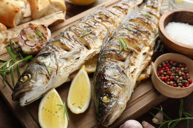 Ahşap masada, ekmek, biberiye ve limonla servis edilen lezzetli kavrulmuş deniz kabuğu balığı. Ev yapımı deniz ürünleri yemeği.