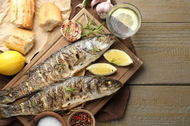 Ahşap masada ekmek, biberiye ve limonla servis edilen kızarmış deniz kabuğu balığı, düzlük ve yazı için yer. Ev yapımı deniz ürünleri yemeği.