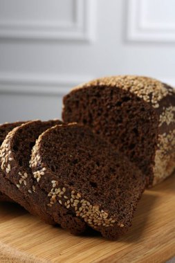 Taze çavdar ekmeği parçaları, tahtanın üzerinde tohumlar açık gri duvara karşı, yakın plan.