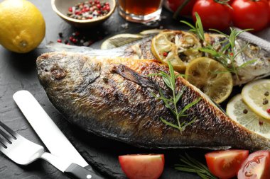 Siyah masada servis edilen lezzetli kızarmış dorado balığı, yakın plan. Ev yapımı deniz ürünleri yemeği.