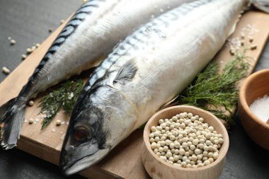 Siyah masada taze çiğ uskumrular ve baharatlar, yakın plan. Deniz ürünleri lezzetleri.