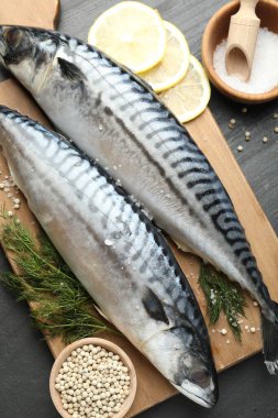Taze çiğ uskumrular ve baharatlar siyah masada, düz yerde. Deniz ürünleri lezzetleri.