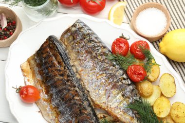 Lezzetli kızarmış uskumrular, baharatlar, domatesler ve patatesler beyaz ahşap masa üzerinde, düz yatak. Ev yapımı deniz ürünleri yemeği.