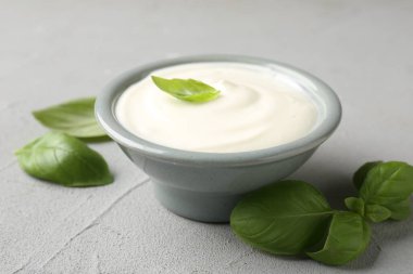 Açık gri masada fesleğenli lezzetli yoğurt, yakın plan.