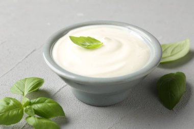 Açık gri masada fesleğenli lezzetli yoğurt, yakın plan.