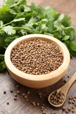 Taze kişniş ve kişniş tohumları ahşap masada, yakın plan.