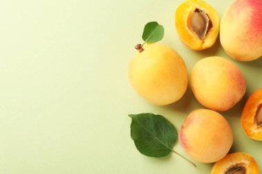 Taze kayısı ve yapraklar soluk yeşil arka planda, düz yerde. Metin için boşluk