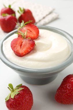 Kasede lezzetli yoğurt ve beyaz masada çilek, yakın plan.