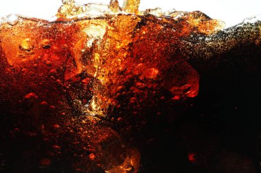 Beyaz zemin üzerinde buz olan ferahlatıcı kolayı cama dökerek, yakın plan