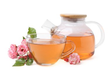 Cam fincanda lezzetli gül çayı, çaydanlık ve beyaz üzerine izole edilmiş çiçekler.