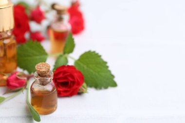 Beyaz masada gerekli yağ şişeleri ve kırmızı güller, yakın plan. Metin için boşluk