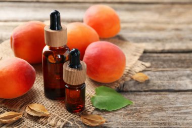 Şişelerdeki, tohumlardaki, yapraklardaki ve olgun kayısılardaki yağlar ahşap masada, yakın plan.