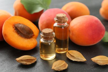 Şişelerde, tohumlarda ve olgun kayısılarda koyu dokulu masalarda, yakın çekim.