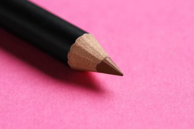 Pembe arka planda kahverengi kaş kalemi, yakın plan. Metin için boşluk