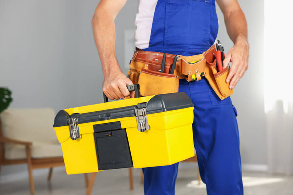Professional repairman with tool box indoors, closeup
