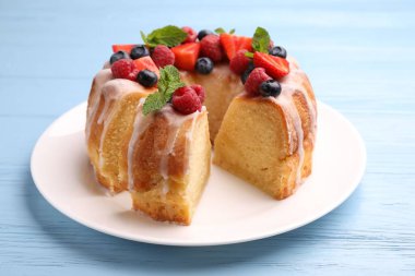 Lezzetli meyveli kek parçaları, açık mavi ahşap masa üzerinde jöle ve nane, yakın plan.