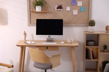 Ev ofisinde ahşap masası, bilgisayarı ve kırtasiyesi olan şık bir iş yeri. İç tasarım