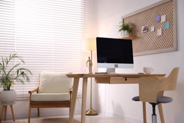 Ev ofisinde ahşap masası, bilgisayarı ve kırtasiyesi olan şık bir iş yeri. İç tasarım