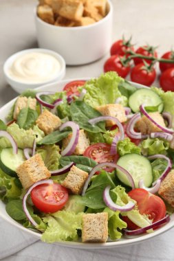 Açık gri masada servis edilen kızarmış ekmek ve sebzeli leziz salata.