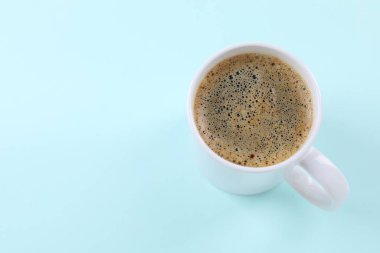 Açık turkuaz arka planda, yukarıda, fincanda Aromatik kahve. Metin için boşluk