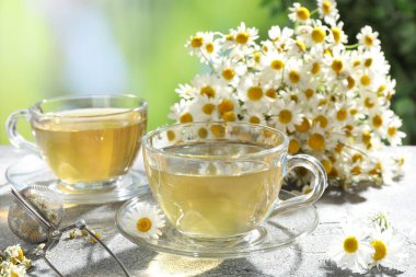 Lezzetli papatya çayı, zerk makinesi ve çiçekler açık gri masada, yakın plan.