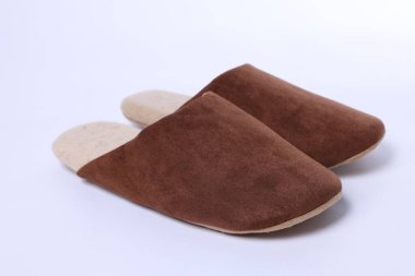 Beyaz arka planda şık kahverengi terlikler, yakın plan.