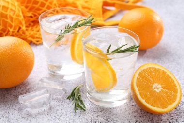 Portakal dilimli maden suyu ve gri masada biberiye, yakın plan.