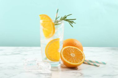 Portakal dilimli soda ve beyaz mermer masada biberiye.