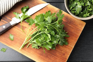 Taze aromalı maydanoz ve bıçak siyah ahşap masada, düz yatıyordu.