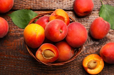 Hasır sepetin içinde nefis olgun kayısılar Tahta masada, düz bir şekilde yatıyordu