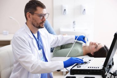 Klinikte kadının tiroid bezini ultrason taraması yapan sonograf.