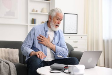 Üst düzey bir adam evde bilgisayarla doktorla görüşüyor.