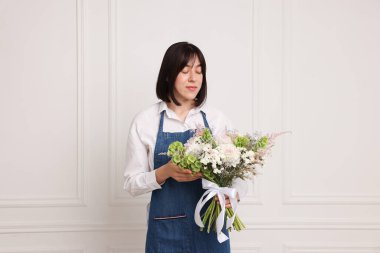 Beyaz duvarın yanında güzel çiçek buketi olan bir çiçekçi.