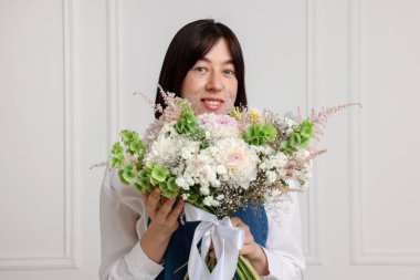 Beyaz duvarın yanında güzel çiçek buketi olan bir çiçekçi.