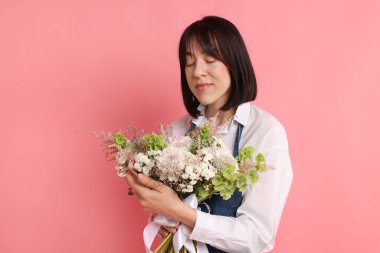 Pembe arka planda çiçek buketi olan bir çiçekçi.