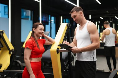 Spor salonunda profesyonel antrenörü olan genç bir kadın.