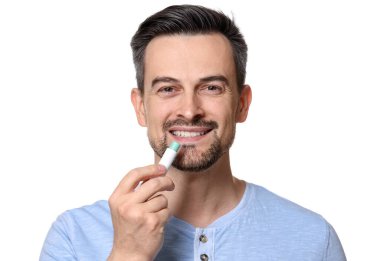 Gülümseyen adam beyaz arka planda dudaklarına merhem sürüyor.