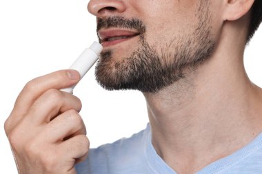 Gülümseyen adam dudaklarına merhem sürüyor. Beyaz arka planda, yakın plan.